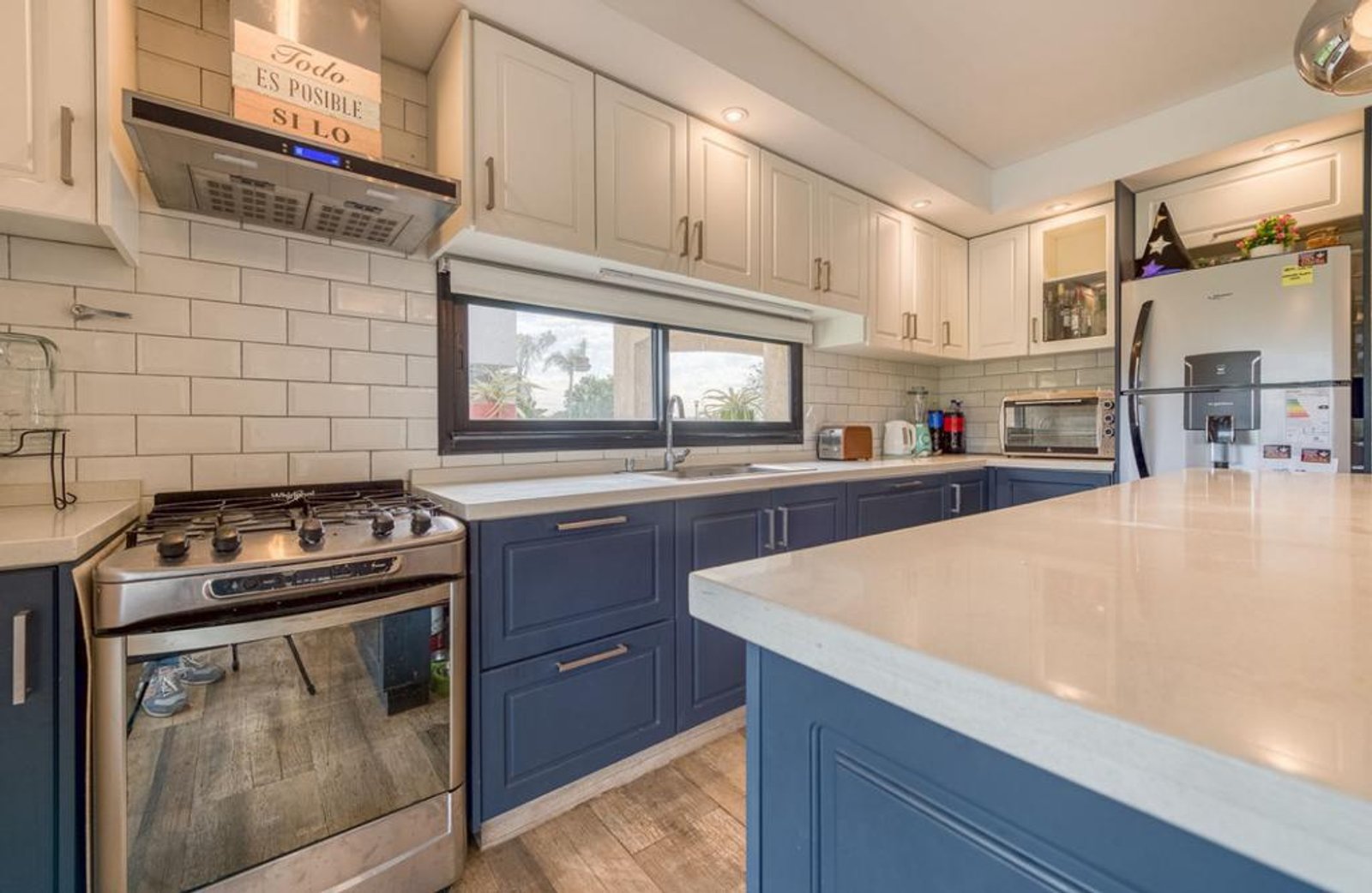 Cocina moderna con gabinetes blancos y azules, mesada de mármol y ladrillos — proyecto Muebles de cocina Laqueados, por Licefe Carpentry SRL, en Ituzaingó